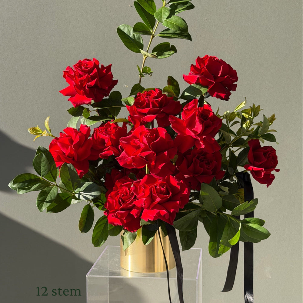 12 red Colombian roses hand-reflexed with foliage in a brushed gold rose pot by Bloom Drop Sydney