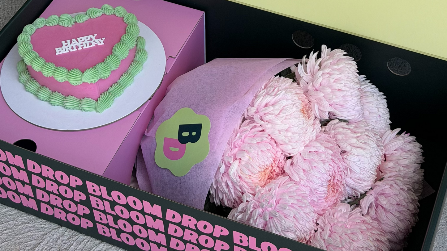 Floral arrangement and cake in a box with 'Blooms for the Bold' branding.