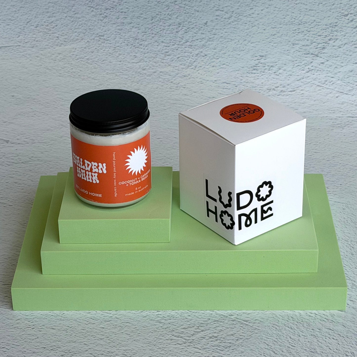 Candle and packaging with 'Ludo Home' branding on a light gray background